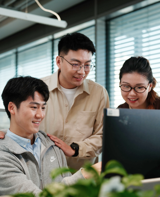 Three colleagues gathered around a computer